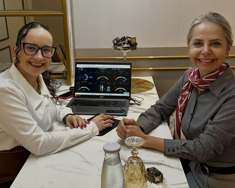 A nutricionista e uma paciente sorrindo à mesa, com o resultado da bioimpedância no computador