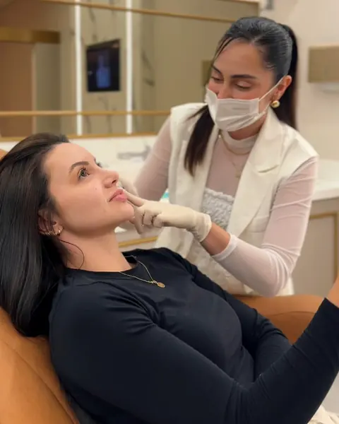Dra. Franciele Nascimento examinando o rosto de uma paciente na cadeira